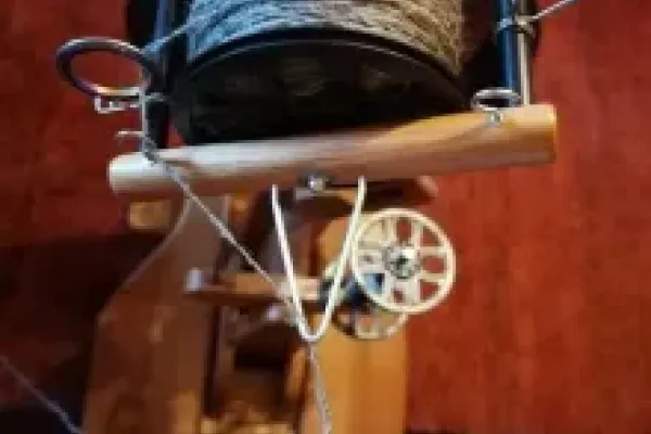 Spinnfaden, der von zwei Fingern gehalten wird am Spinnrad