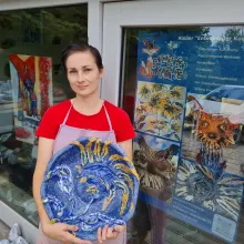 Ich stehe vor dem Eingang zum Atelier mit einer blau-gelben Keramikschale