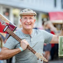Turinsky mit Mütze aus einem alten Kartoffelsack. Hält zwei Instrumente in die Luft.