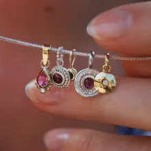 Diverse Anhänger aus Gold und Silber mit bunten Edelsteinen.