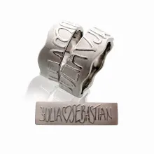 UNENDLICH 8mm: zwei individuelle Trauringe mit geteiltem erhabenem Text, hier: Julia Herz Sebastian, und gewelltem Rand aus 585 Weißgold. Die Ringe sind jeweils 8mm breit.