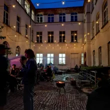 Das Foto zeigt einen Abend im Hof mit Lagerfeuer und Lichterkette.