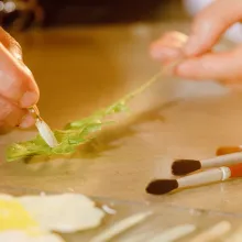 ein Löwenzahnblatt erhält mittels Handarbeit seine charakteristische Zeichnung