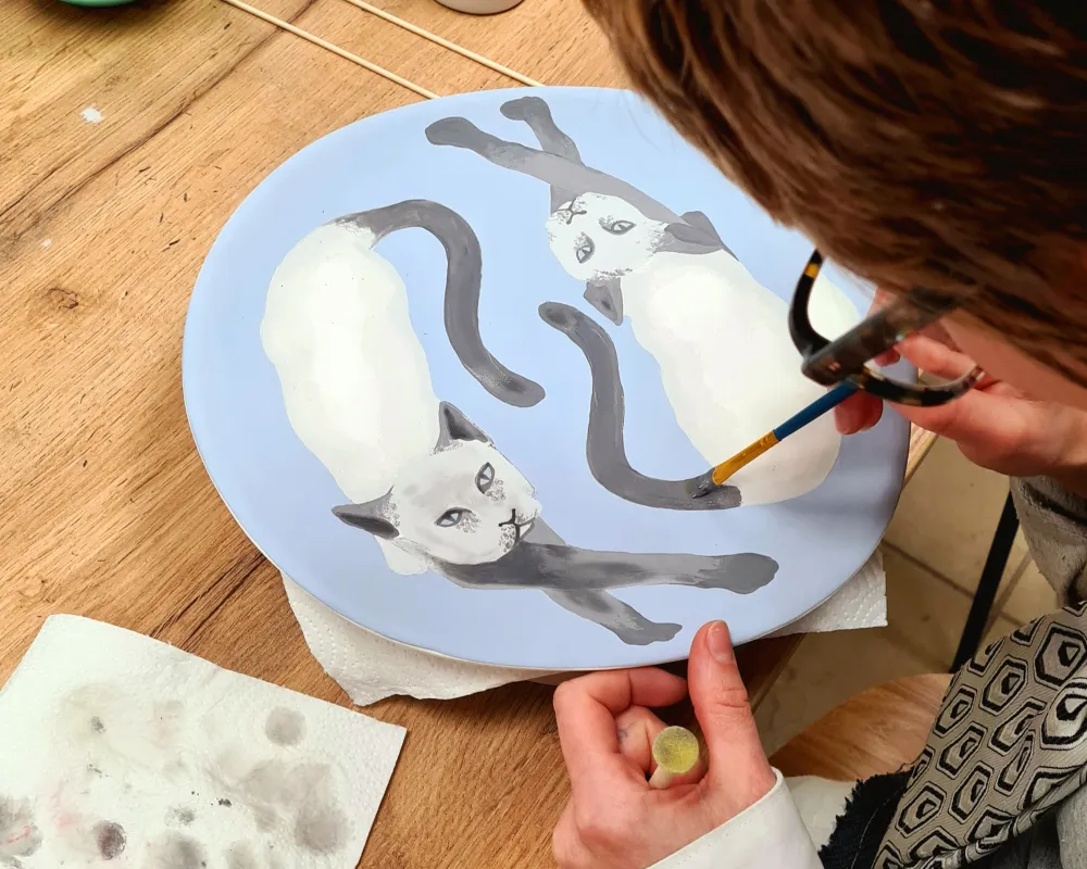 Foto Sabine Haugg Keramikrohling der mit 2 Katzenmotiven mit Keramikfarben bemalt wird