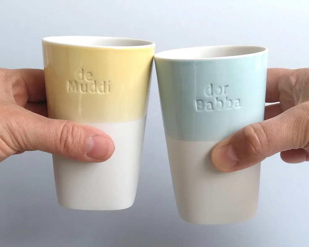 2 Becher mit eingestempelten sächsischen Wörtern (de Muddi und dor Babba), mint und gelb