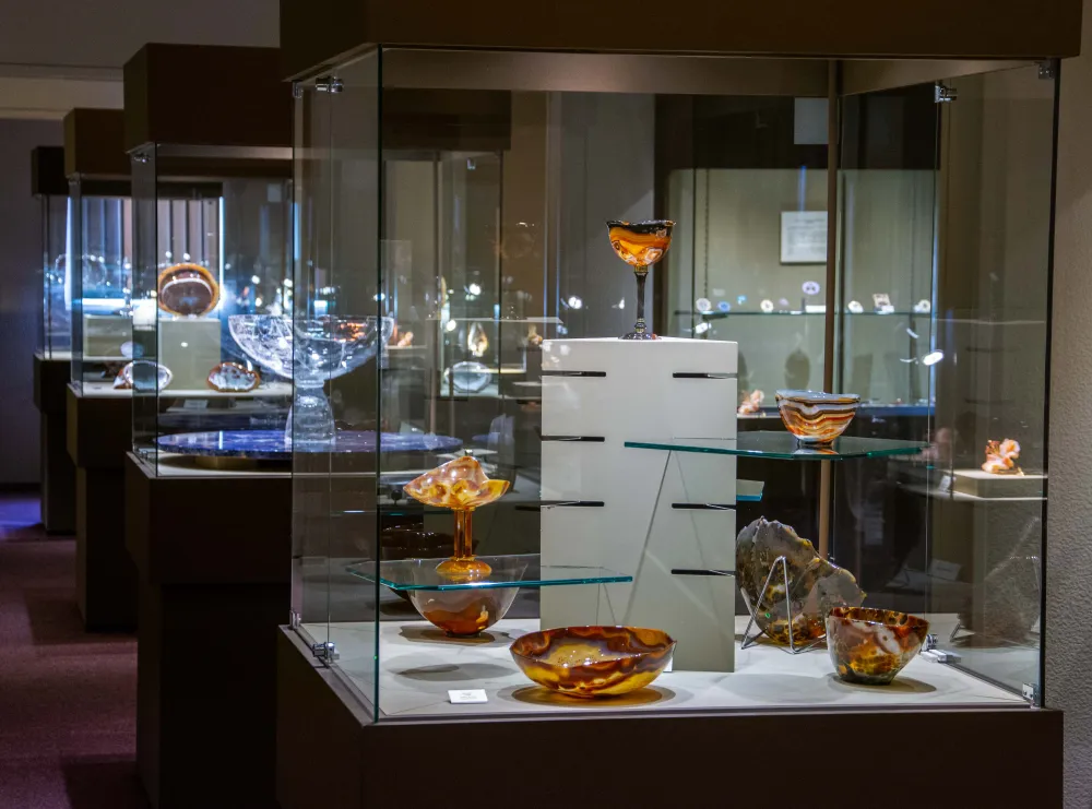 Ausstellungsraum mit mehreren Vitrinen, die verschiedene kunstvoll gravierte Schalen aus Edelsteinen zeigen