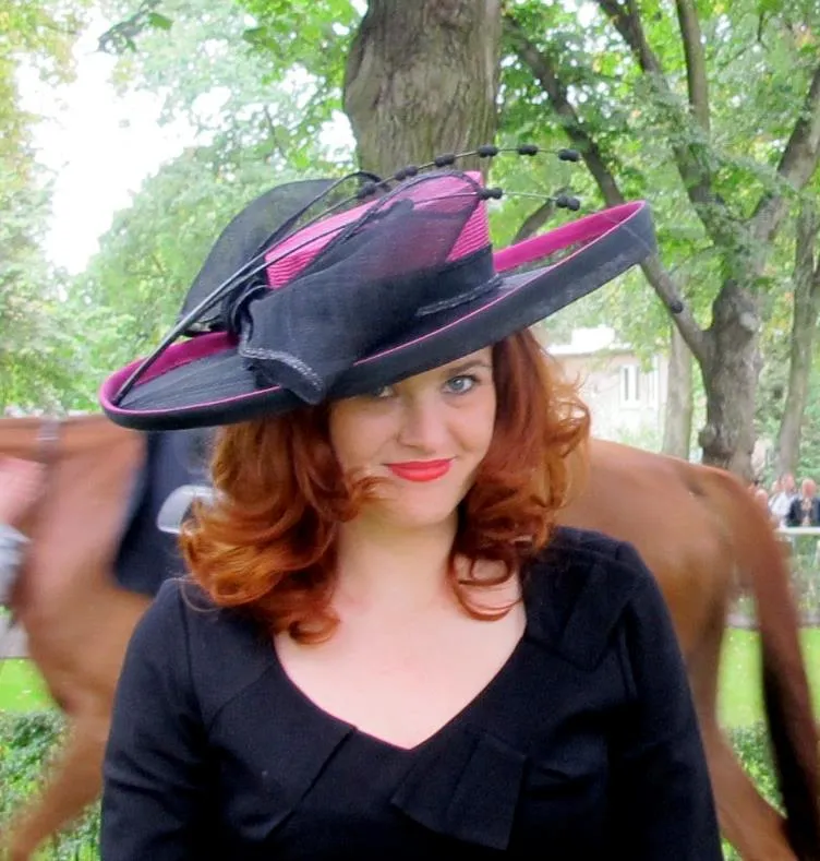 Frau mit Sommerhut vor einem Pferd.