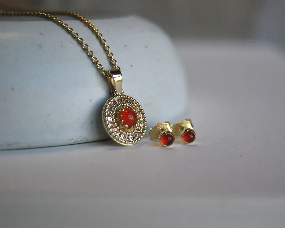 Schmuckset bestehend aus Anhänger und Ohrsteckern, ganz filigran gemustert aus Gold mit orangenen Carneol. 