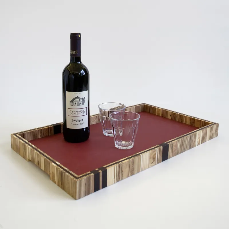 Ringeltablett: Gläser, Teller und Pasta, alles läßt sich mit diesem Tablett von A nach B transportieren und punktet deutlich sichtbar mit seiner charakteristischen Bauweise. Der Materialmix aus Produktionsresten von Tischlereien wird durch eine Massivholzeinlage optisch und statisch zusammengehalten. Der mit Linoleum  belegte Boden, setzt in verschiedenen Farben einen fröhlichen oder zurückhaltenden Akzent. 