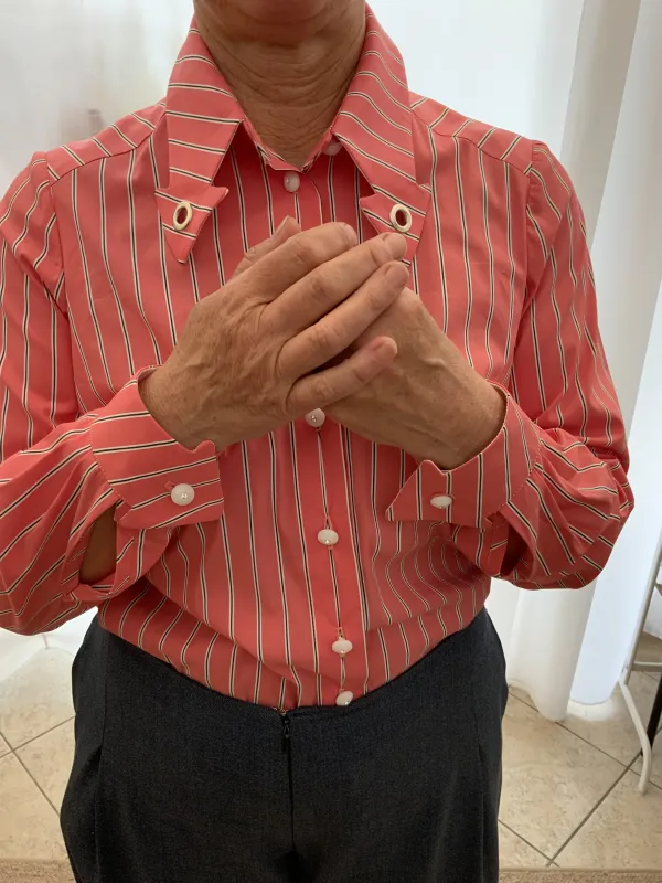 Dies ist eine maßgeschneiderte Bluse in einem sportlichen Schnitt. Sie hat einen zarten lachston mit weißen Streifen und geknöpft wird sie mit weißen Perlmutknöpfen. Die Manschetten sind in Pfeilform zugeschnitten passend zum Kragen.