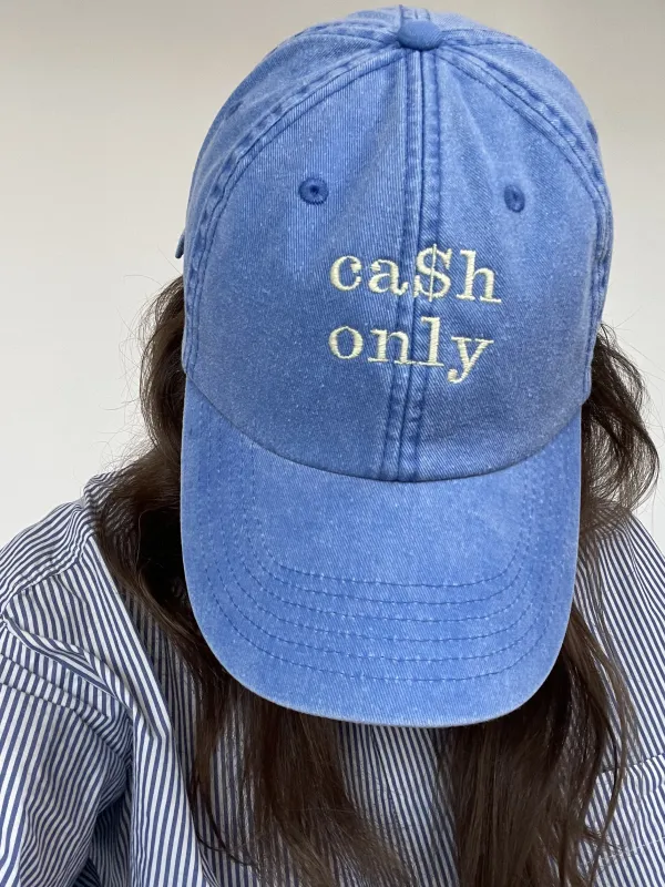 Model mit kornblauem Cap in stonewashed Optik, das vorne mittig mit einer Stickerei CASH ONLY in Buttermilk Yellow ca. 5x5 cm groß,versehen ist