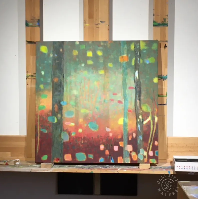 Auf einer Wandstaffelei steht ein Bild. Der Blick in einen Wald von Baumstämmen, Der Boden ist rot / brau, Stämme und Hintergrund sind grün / braun, Bildmitte ist heller gemalt. Bunte Blasen fliegen zwischen den Stämmen. 