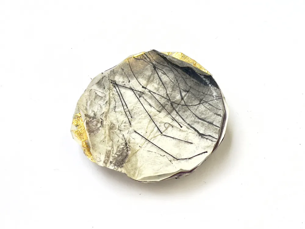 Ein rundes Objekt aus farbig gestaltetem Papier, das an eine Landschaft von oben erinnert.