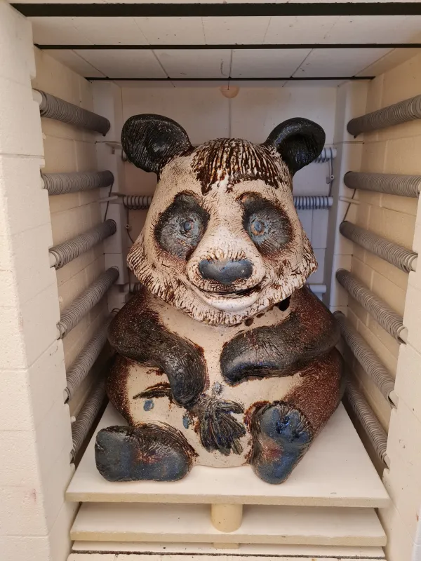 Bär aus Keramik sitzt in einer Holzkiste
