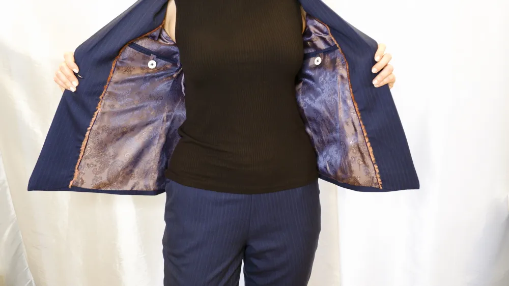 Maßgeschneiderter Hosenanzug in dunkelblau mit Nadelstreifen. Die Innenverarbeitung ist eine Augenweide und lädt förmlich dazu ein, die Jacket anzuziehen.