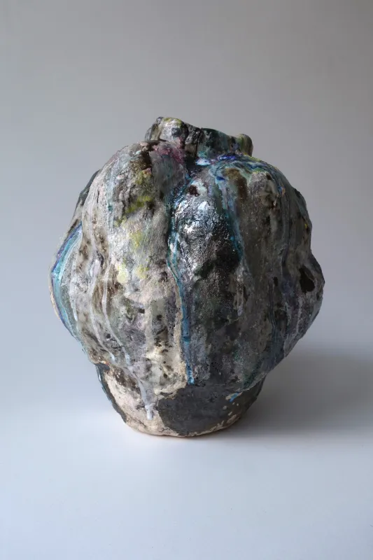 Lonni Wong Colorful Vessel, 2024 shows a dented dark brown vase with lots of colorful glazes.