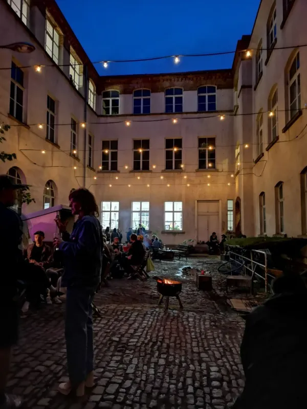 Das Foto zeigt einen Abend im Hof mit Lagerfeuer und Lichterkette.