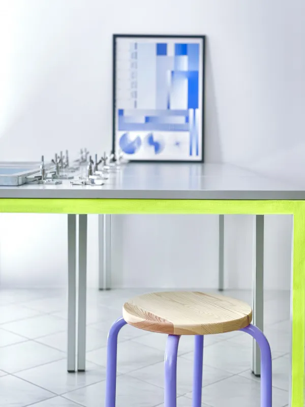 Workshoptisch mit Hocker im Vordergrund und Bilderrahmen auf dem Tisch
