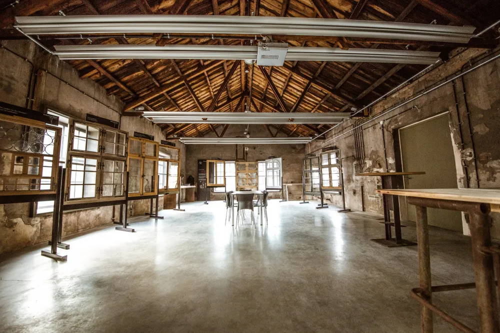 Showroom der Holzmanufaktur Rottweil im ehemaligen Pumpenhaus. Unverputzte Wände, hohe Decken und im Raum stehen mehrere restaurierte Fenstermodelle.